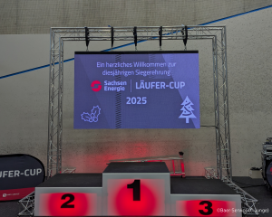 Aufnahme vom Siegerpodest ohne Personen mit Präsentation im Hintergrund - Siegerehrung 2025